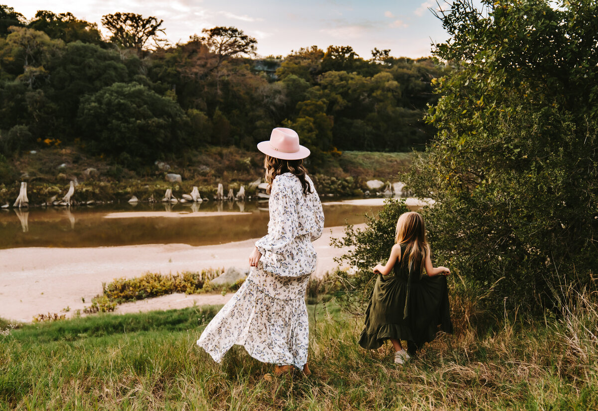 Family Photographer, Mom and daughter walk through the grass to the river