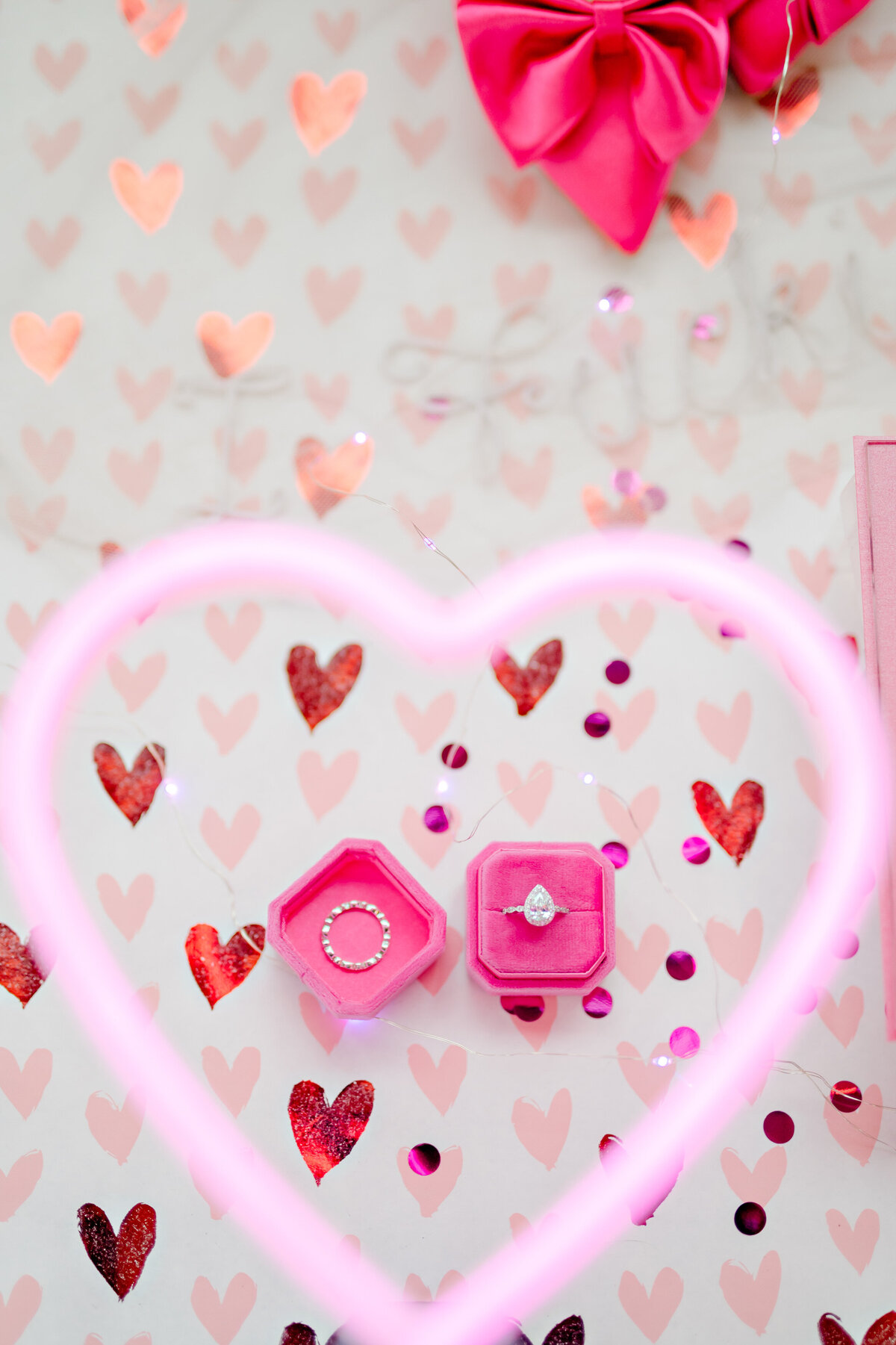 Brides' wedding rings with pink neon heart sign around it