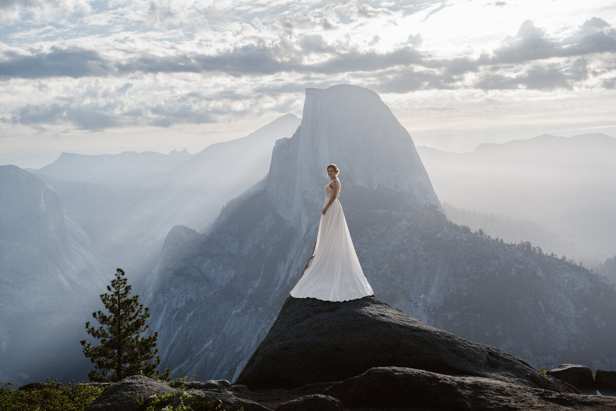 A person in a wedding dress standing at the top of a rock