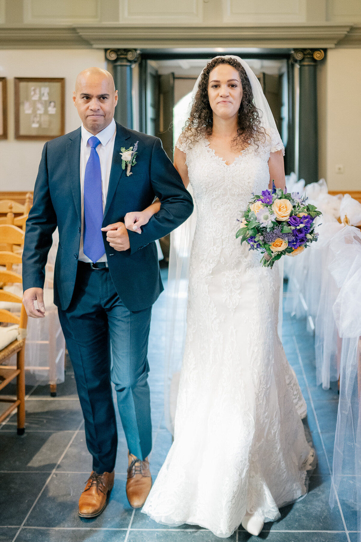A bride walks down the aisle of the historic monumental Van Goghkerkje with her father 