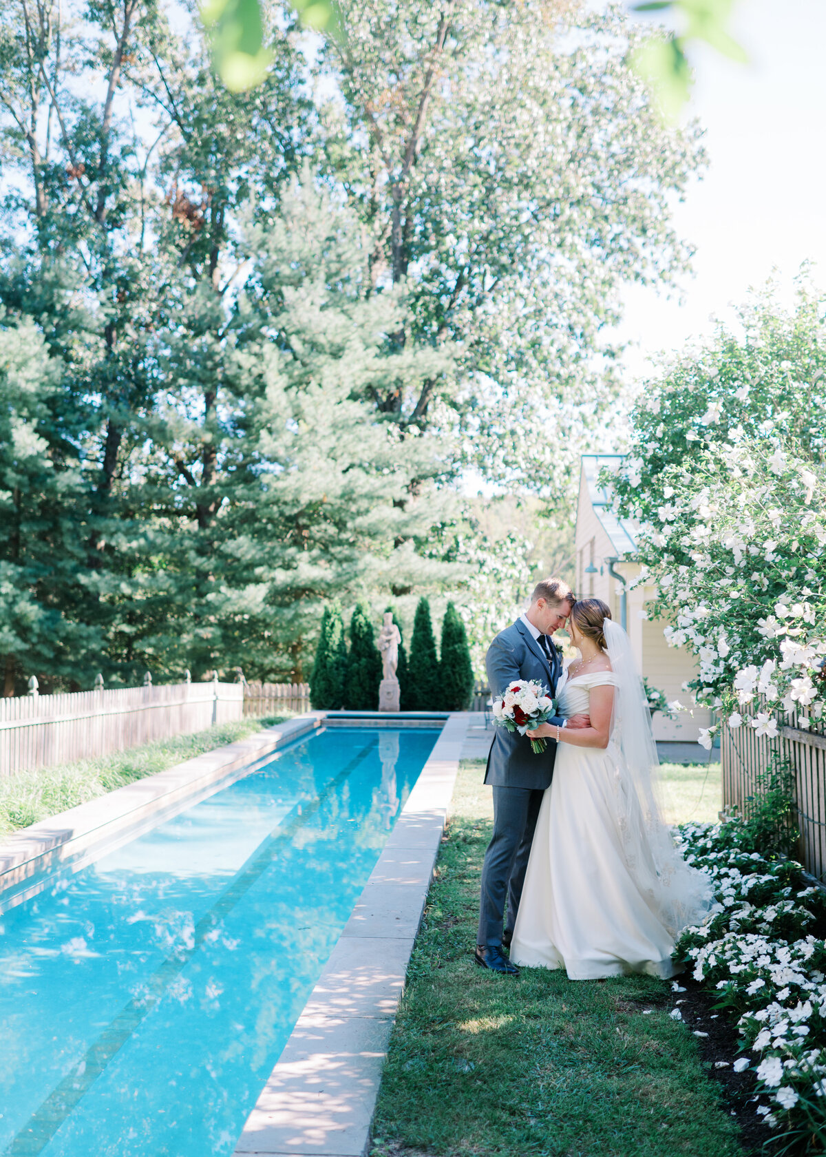 Bride and groom embrace near a pool