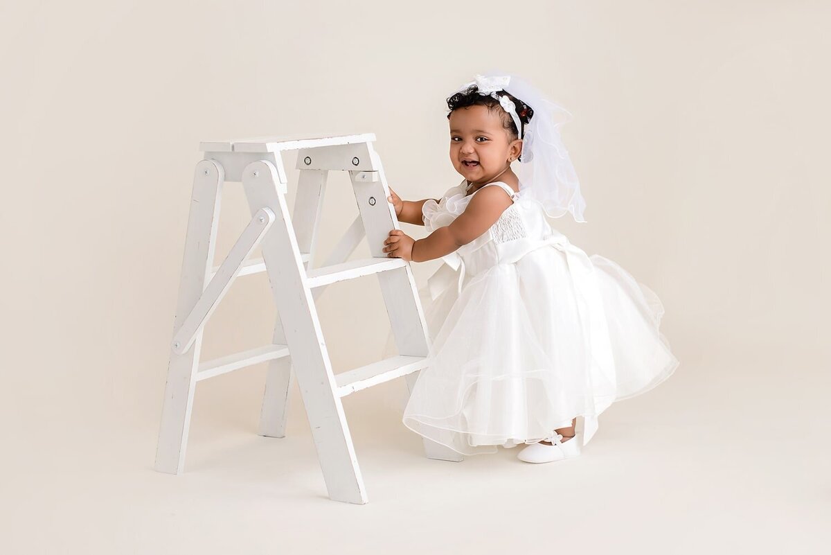 White and cream themed first year birthday session for baby girl in a white dress.