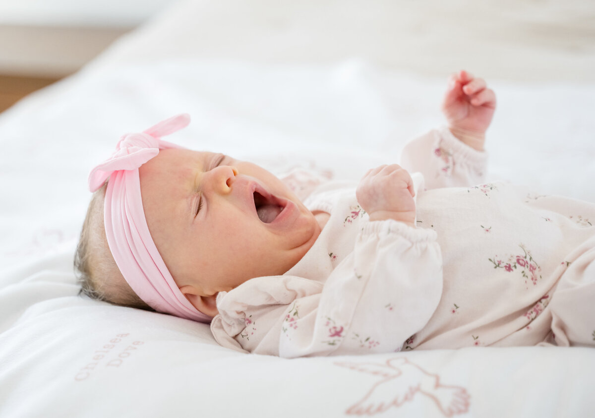 Lifestyle newborn portrait of newborn baby girl yawning