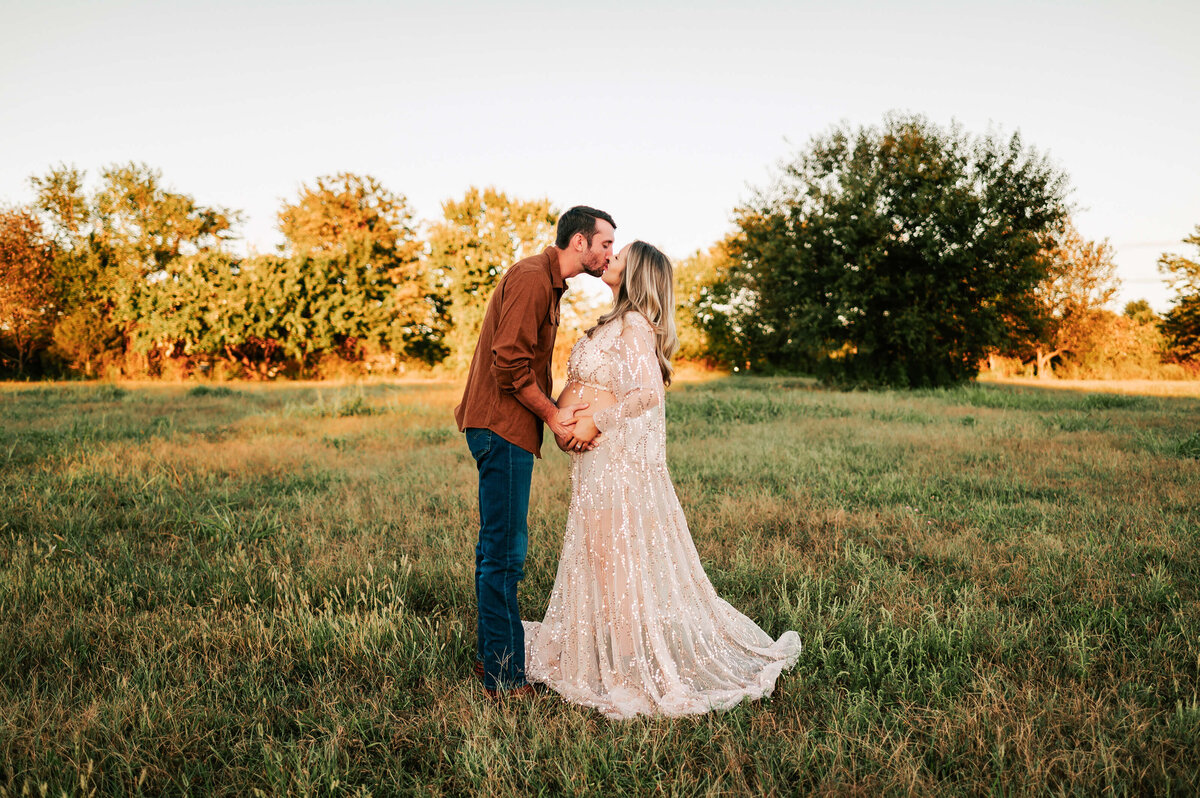 maternity pictures in Springfield MO of pregnant couple kissing in open field in Springfield MO