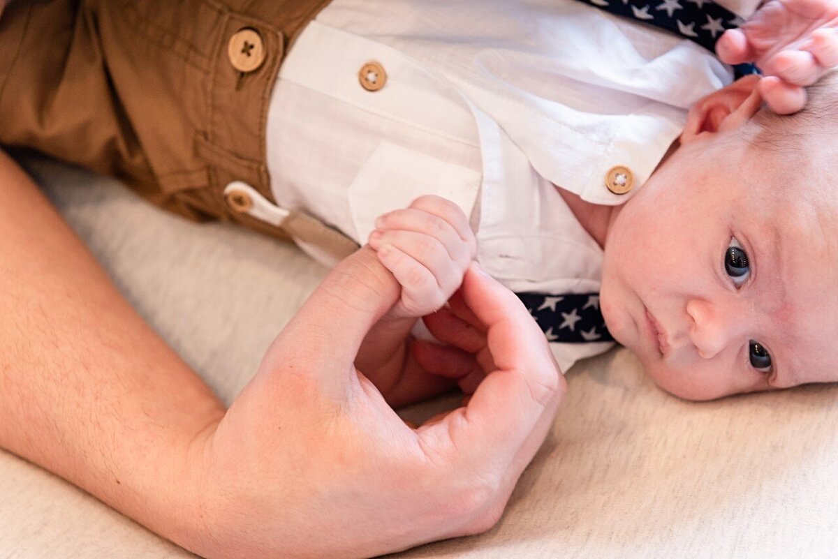 dads hand holding newborn boy