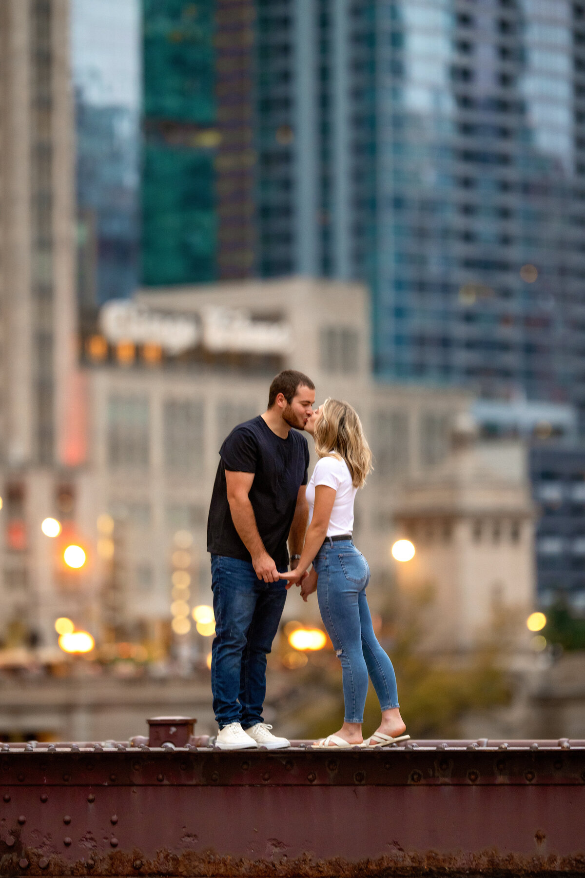 engagement photoshoot on top of red metal bridge with Chicago tribune building in the background