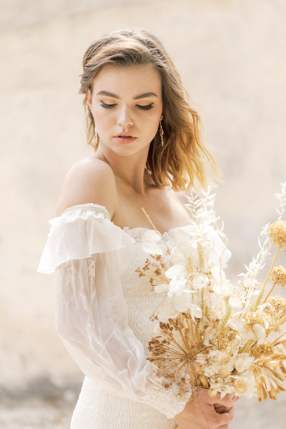 Bride holds her bouquet in the air and smiles during bridal portrait session