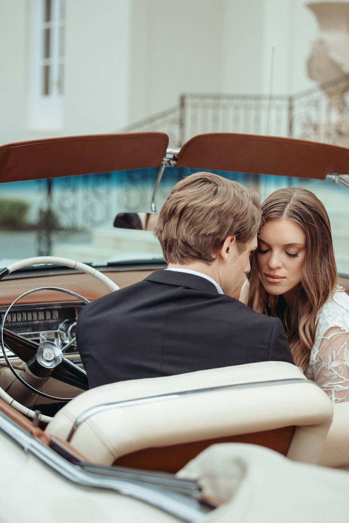 Bride and groom sharing an intimate moment in a vintage convertible with tan interior at a Houston wedding.