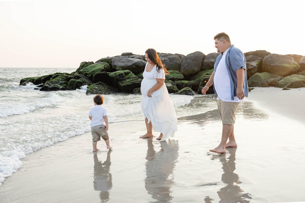 Pregnant woman with her husband and young son enjoying a sunny day at the beach in Long Beach, New York.
