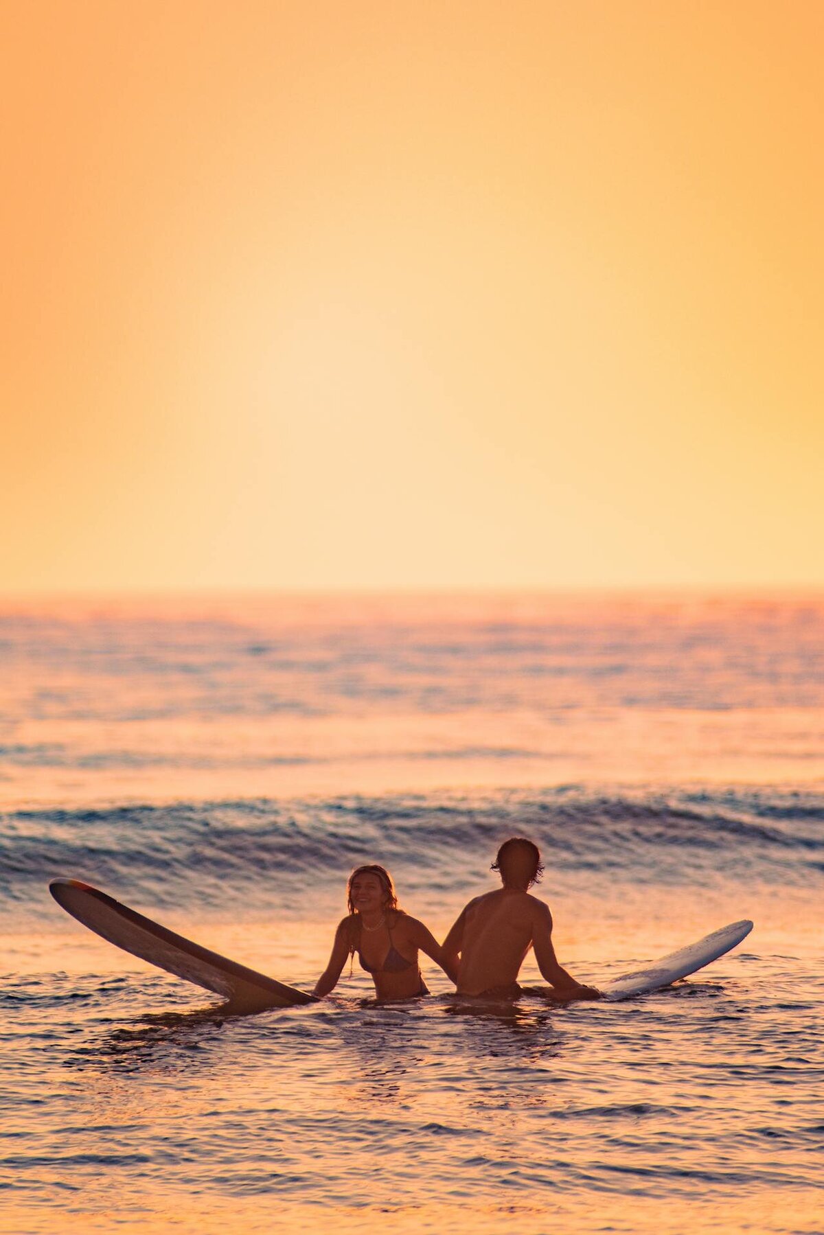 couple surfing in ocean