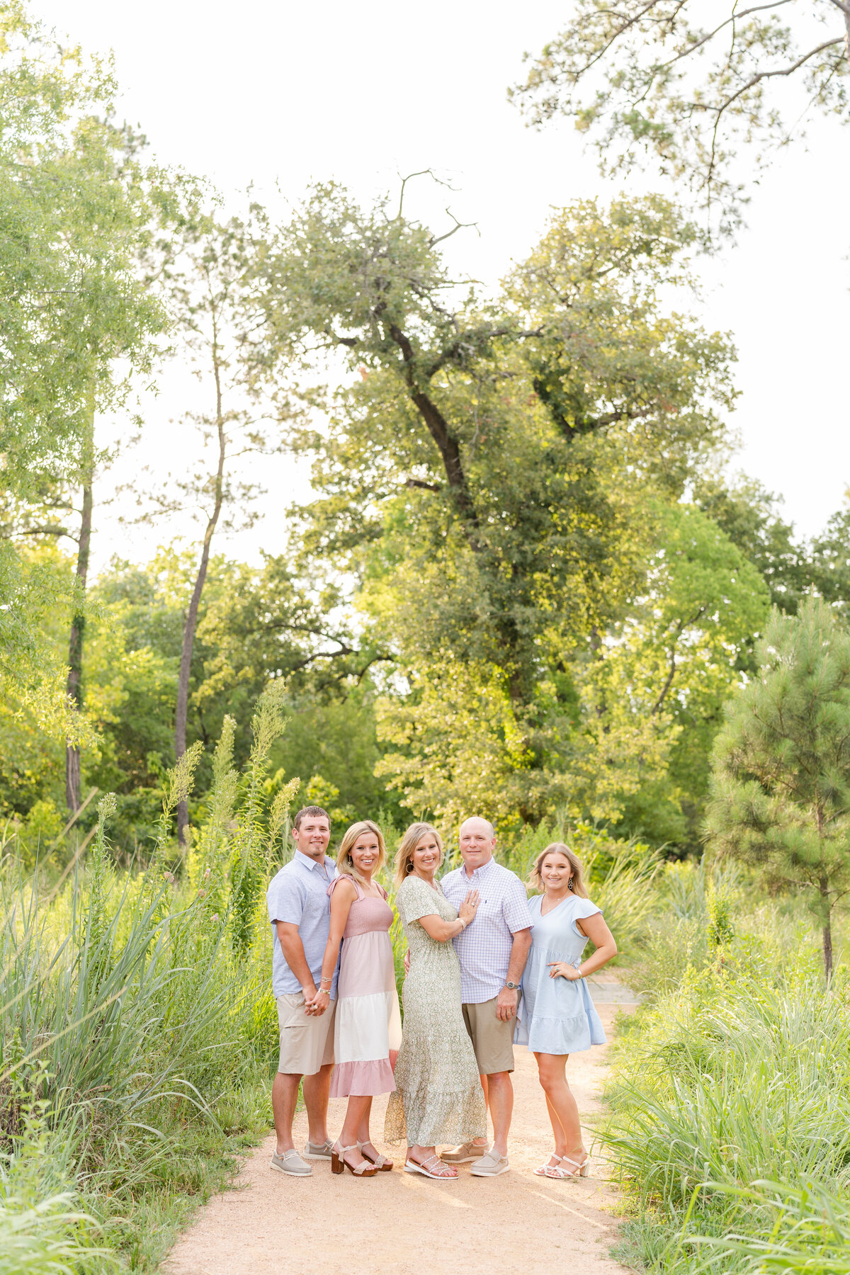 Family in pastel colors smiling at camera surrounded by nature at Houston Arboretum