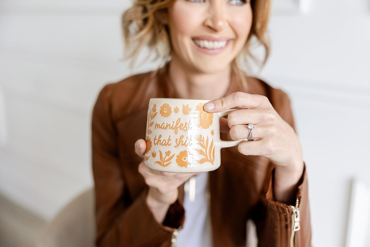 Angie Kircher, Hypnotherapist and Money Mindset Coach holding a coffee mug