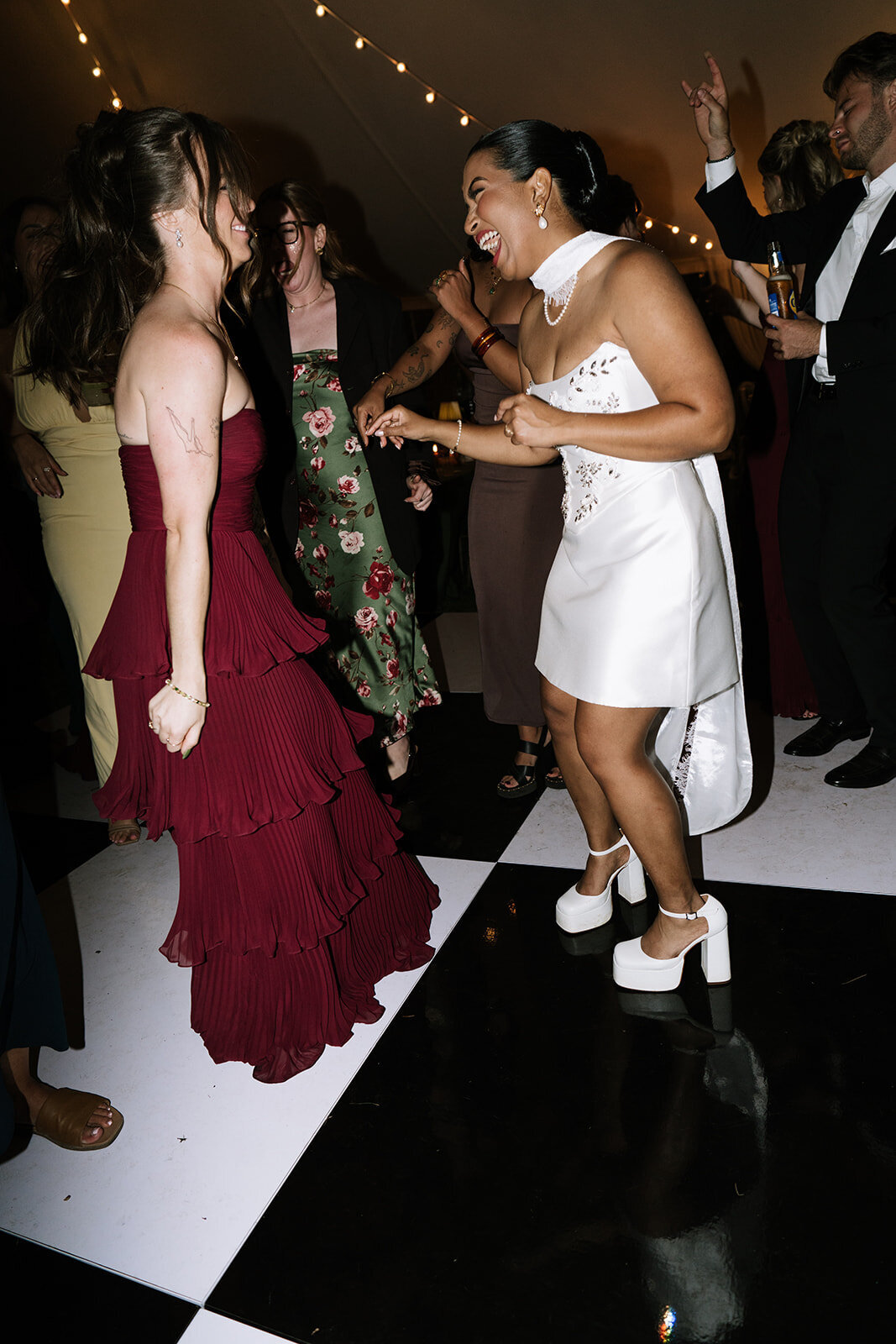 ride dancing with friends under a tented reception — joyful wedding photography capturing energy and movement on the dance floor.