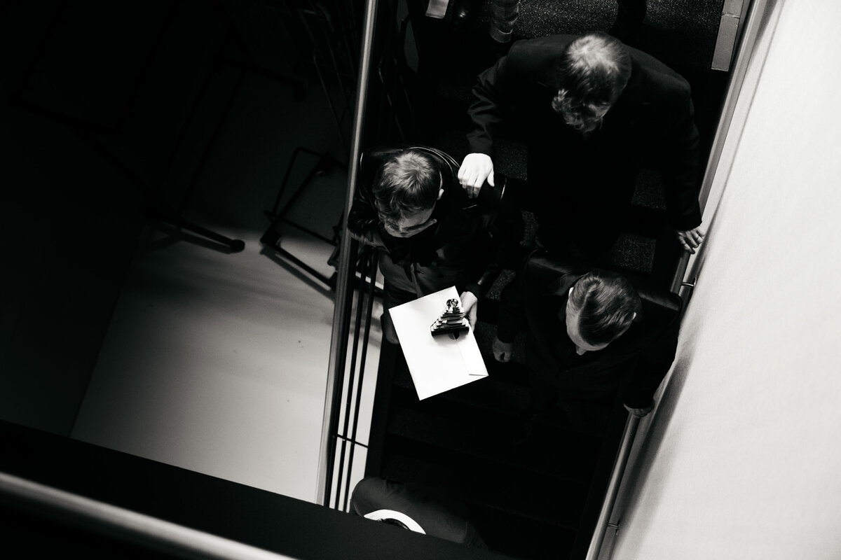 Acteurs van bovenaf gefotografeerd backstage op een trap met award in handen.