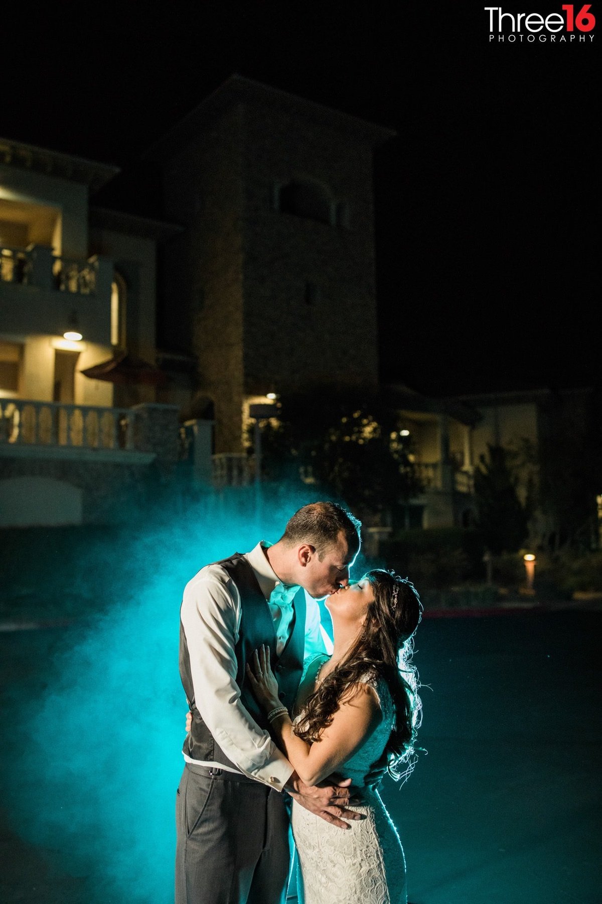 Bride and Groom share a kiss at night with a blue mist behind them
