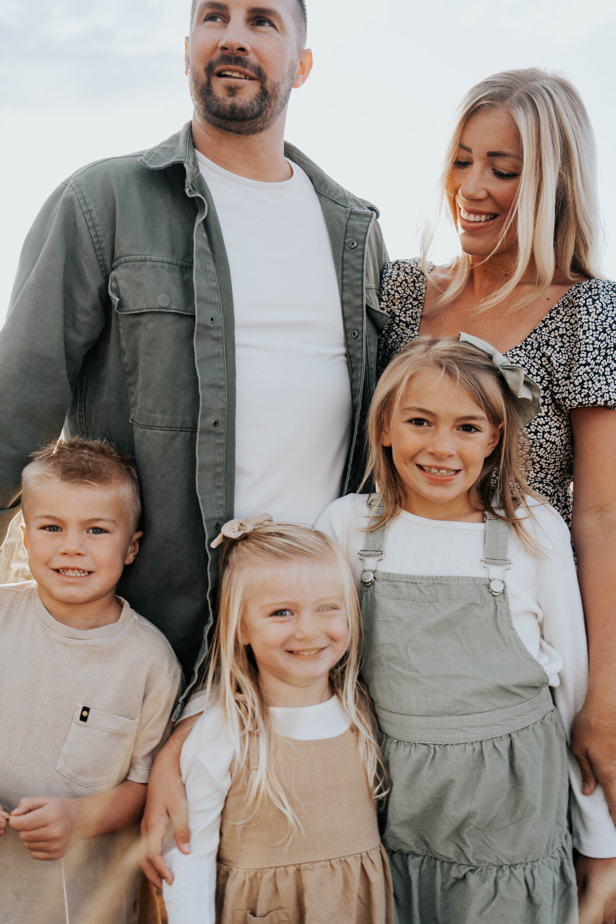 family smiles at the camer toddler girl, little boy and older girl while mother smiles down on them captured by Idaho Falls Family Photographer