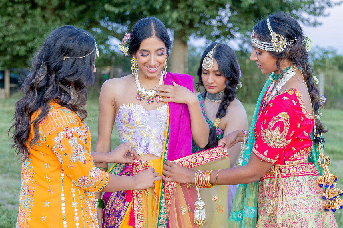 A bride is surrounded by 3 of her friends during a traditional wedding ceremony displaying their culture.