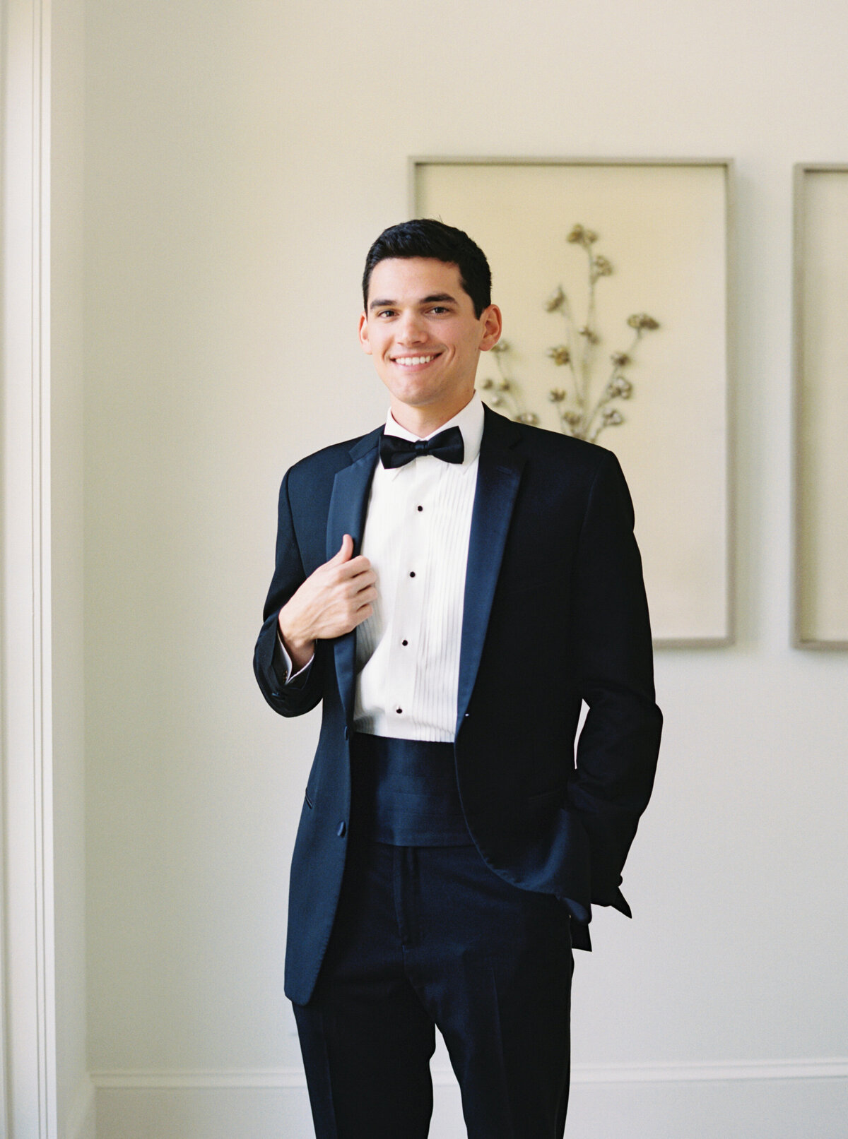Groom preparing for his wedding day, adjusting his suit in a classic moment, captured on film by Morgan Alysse, Louisiana film photographer.