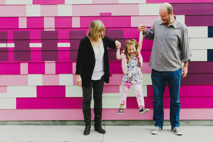 Mom and dad hold child in between them laughing