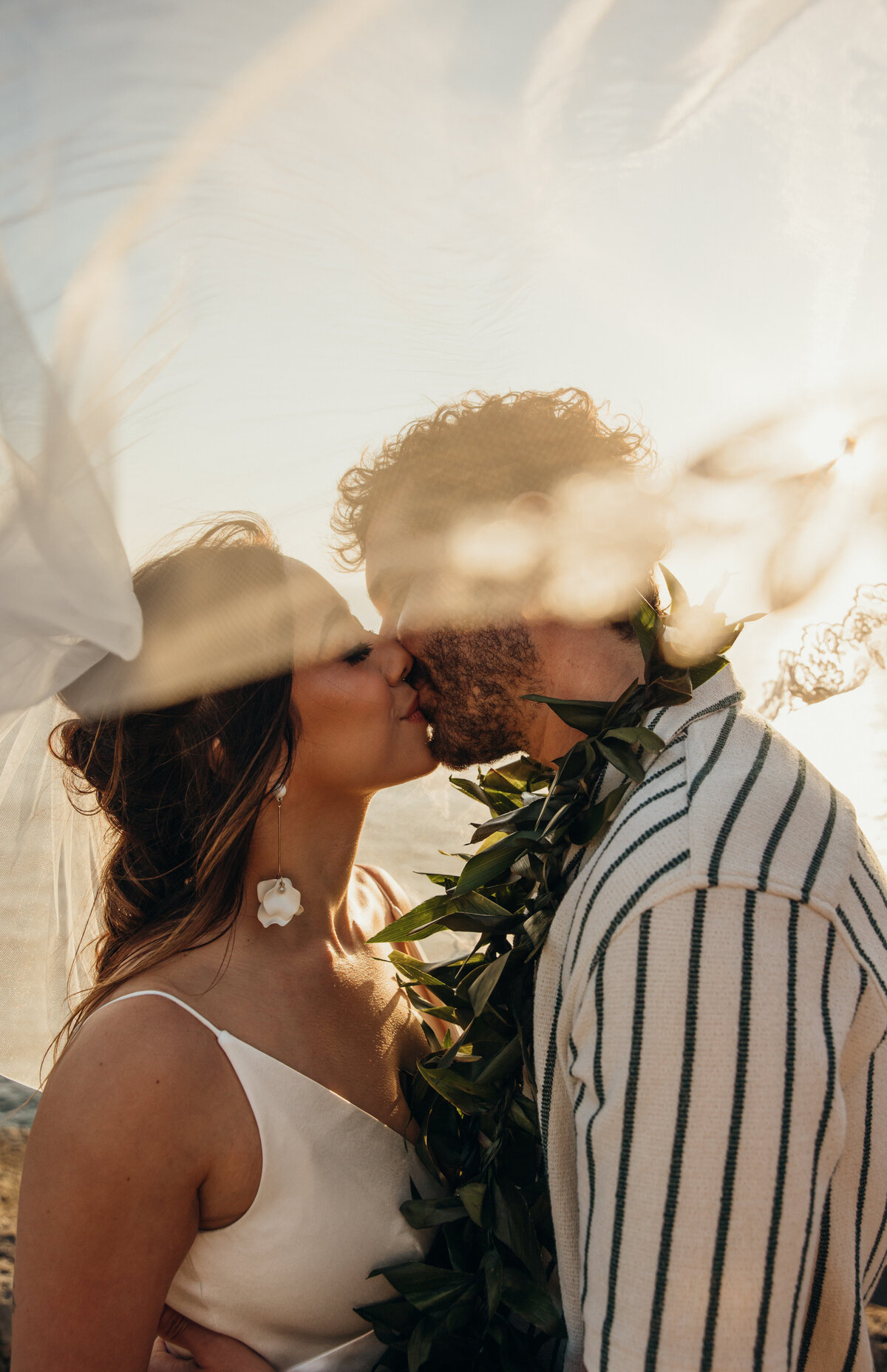 Maui Wedding Photographer captures bride and groom kissing under veil after Maui beach wedding