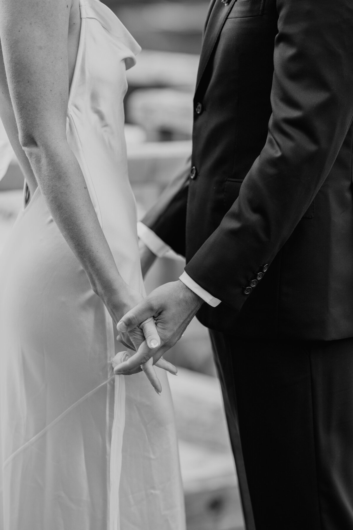 Close-up of couple holding hands in wedding attire
