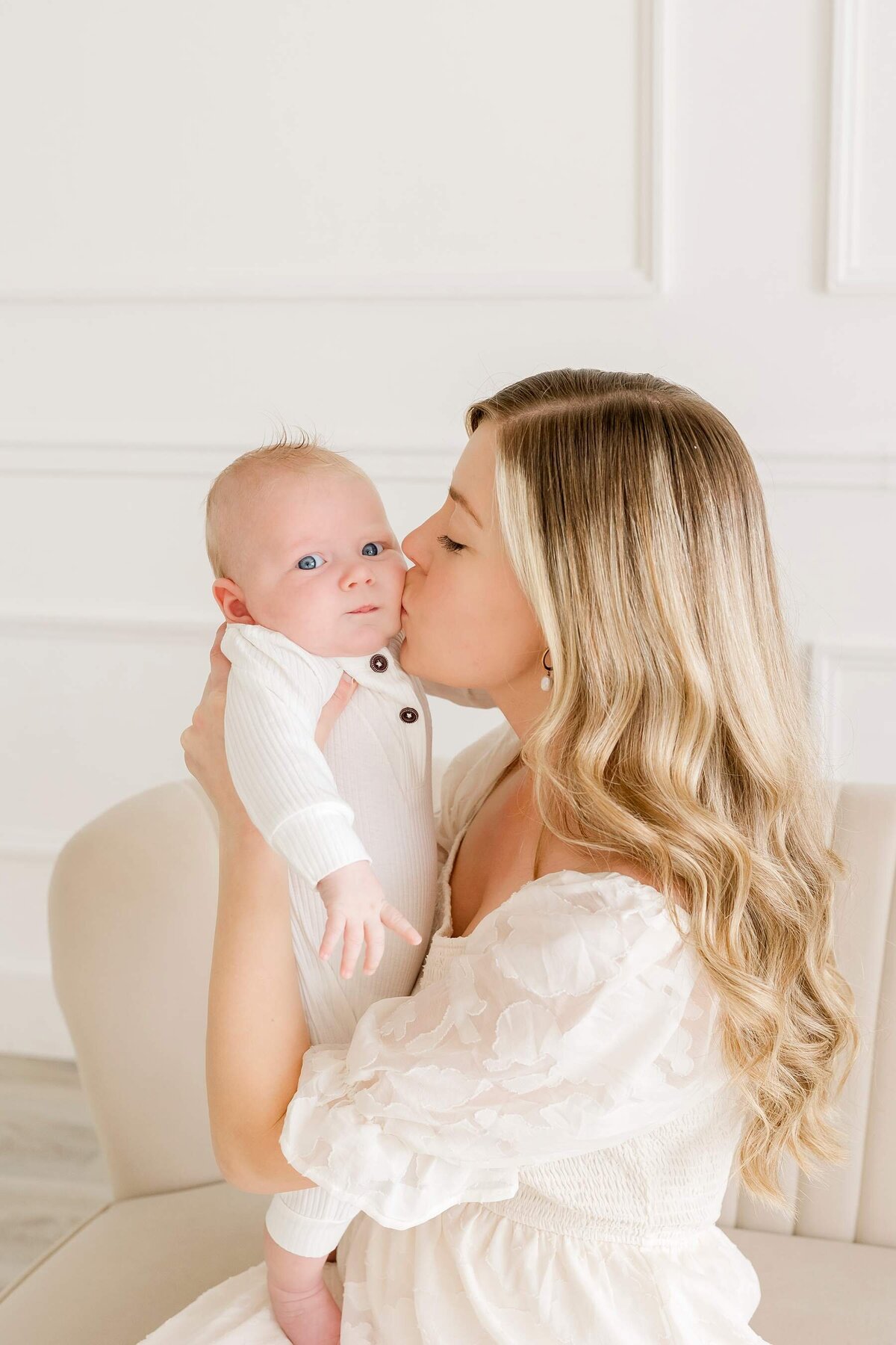 A peaceful, all-white studio sets the stage for an adorable newborn photoshoot