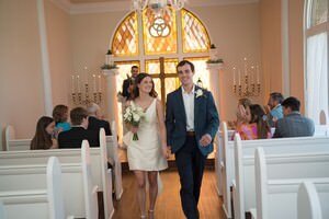 Newlyweds walking down aisle after intimate wedding ceremony in historic St Augustine chapel with stained glass windows, captured by professional wedding photographers