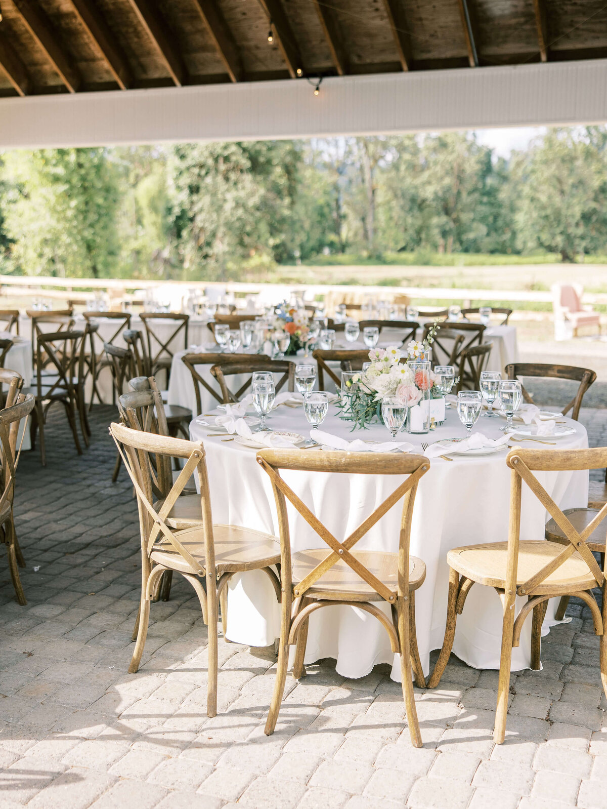 Tables set with tableware, candles and flowers at an outdoor Oregon wedding.