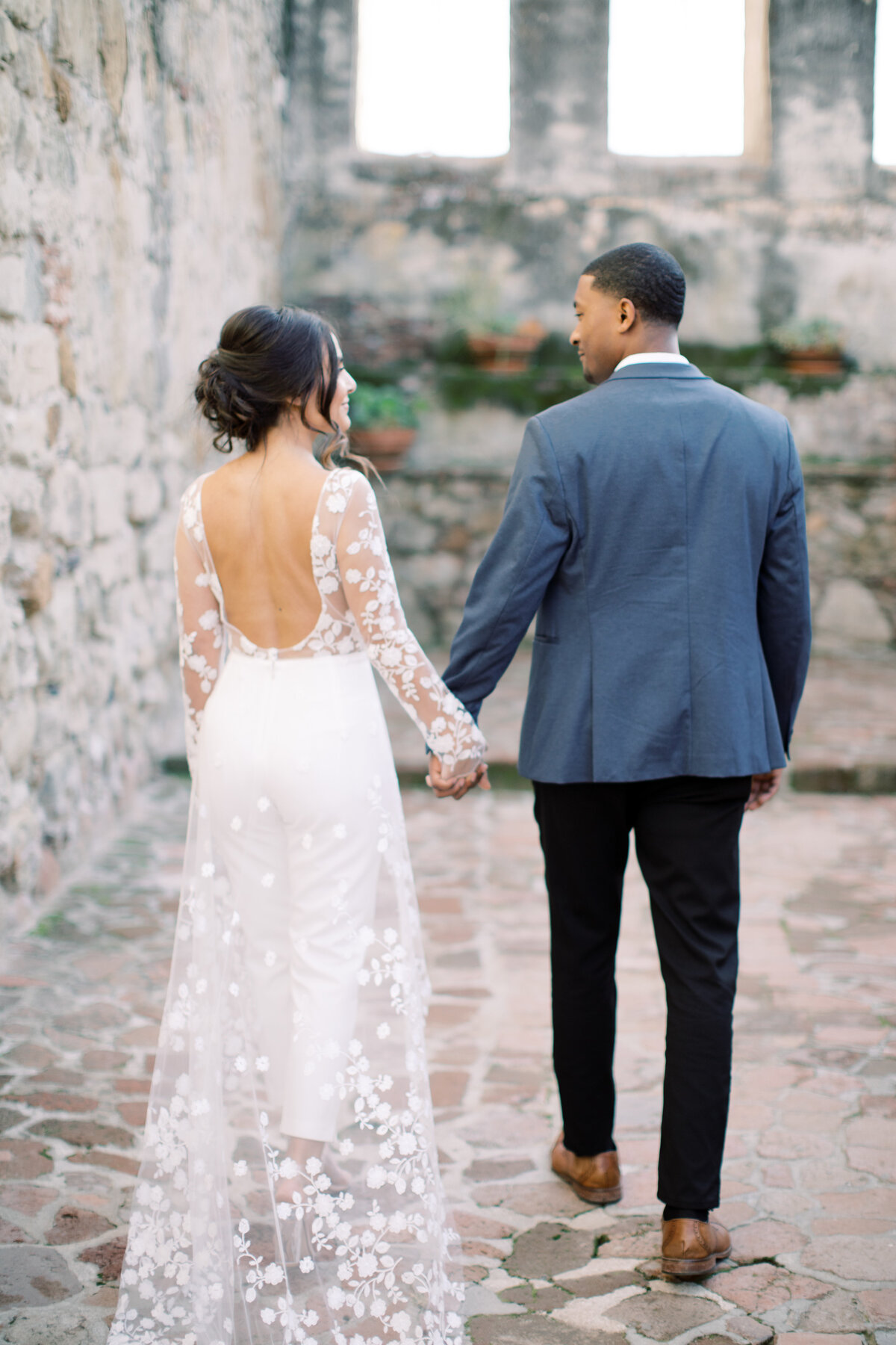 Couple holding hands walking in a courtyard. 
