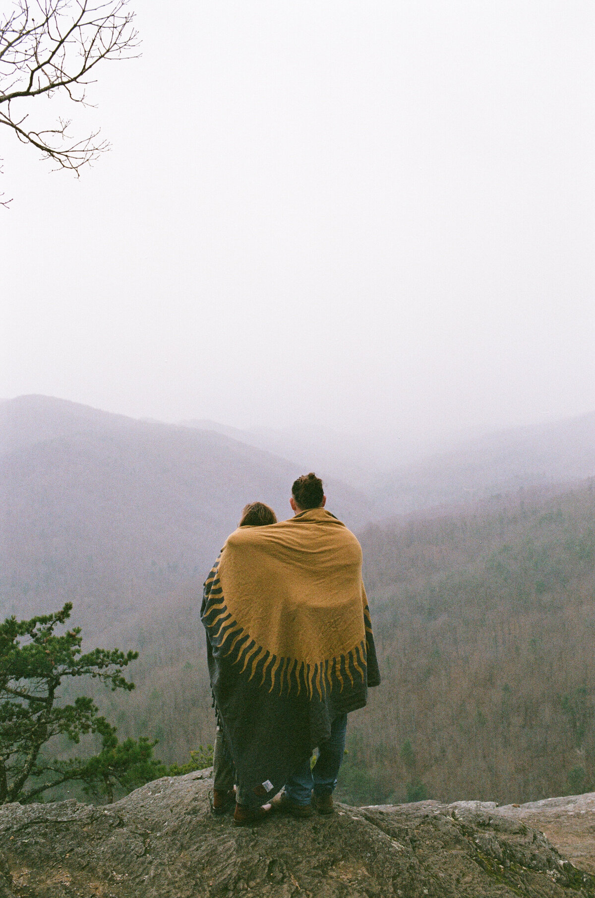film image of couple in blanket overlooking a summit