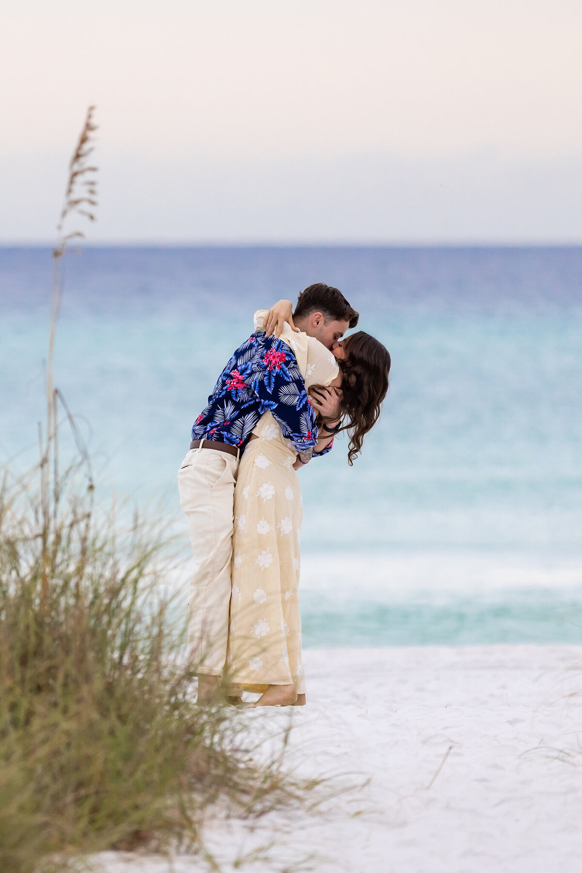 happy couple hugging on beach after man proposes to his girlfriend in Grayton Beach, Florida.