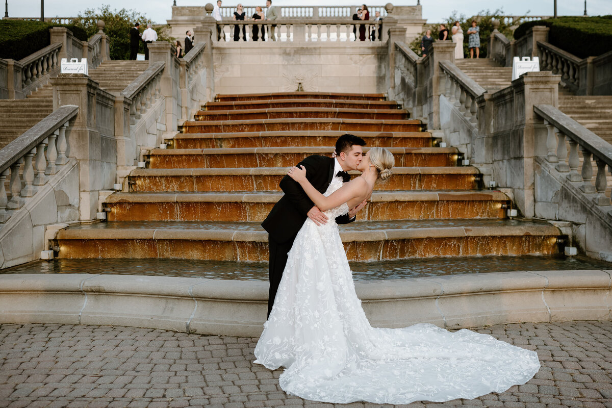 bride and groom kissing by the steps on their wedding day