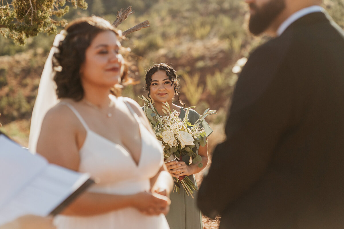A bridesmaid standing behind a wedding couple during their ceremony 