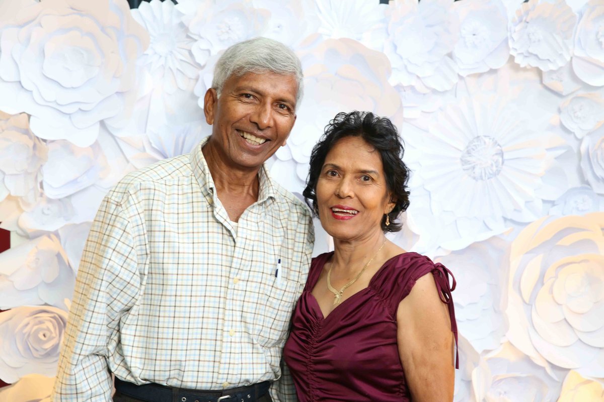 An older man and woman couple smile in front of 3d backdrop. Photobooth by Ross Photography, Trinidad, W.I..