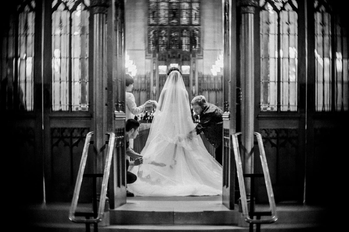A black and white image capturing a bride descending on a grand staircase