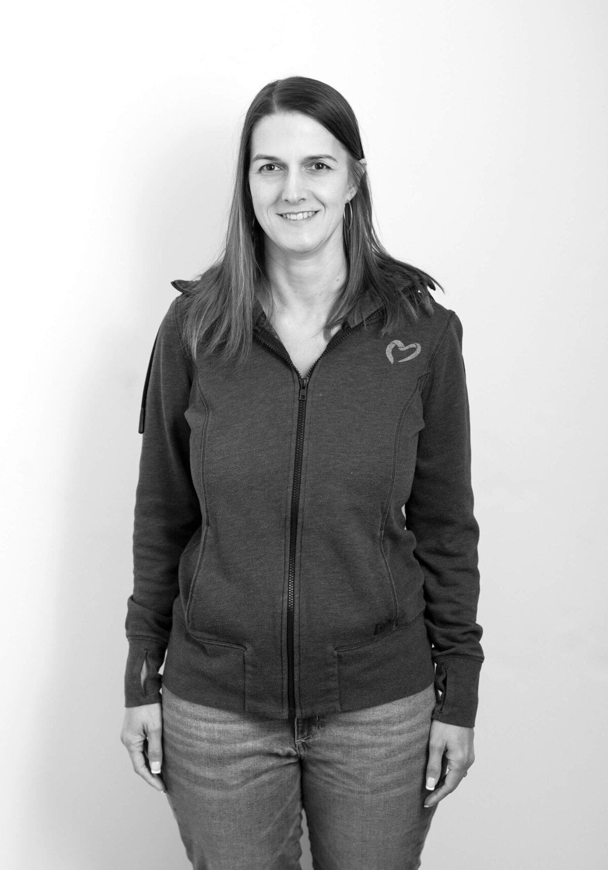 Casual before shot of a woman in a zip-up hoodie, smiling against a plain background.