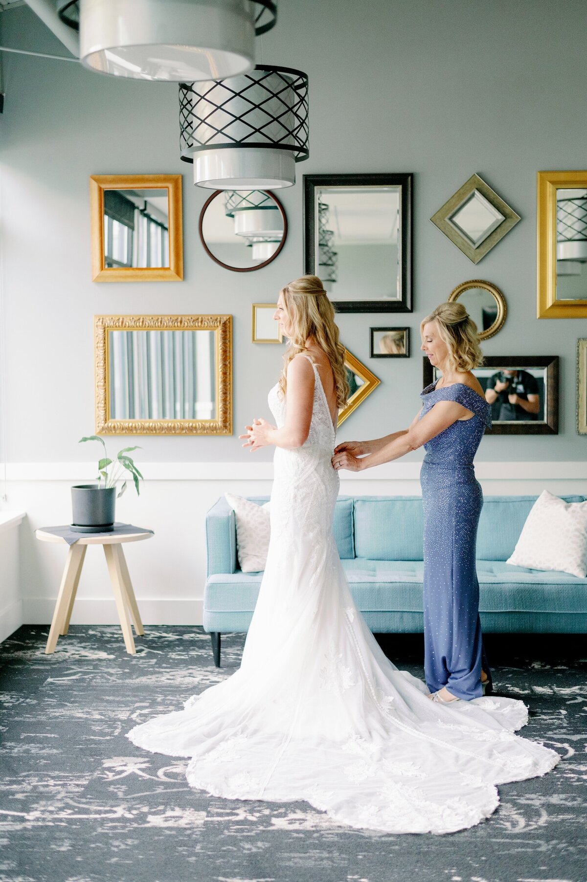 a woman helping a bride fasten her wedding dress