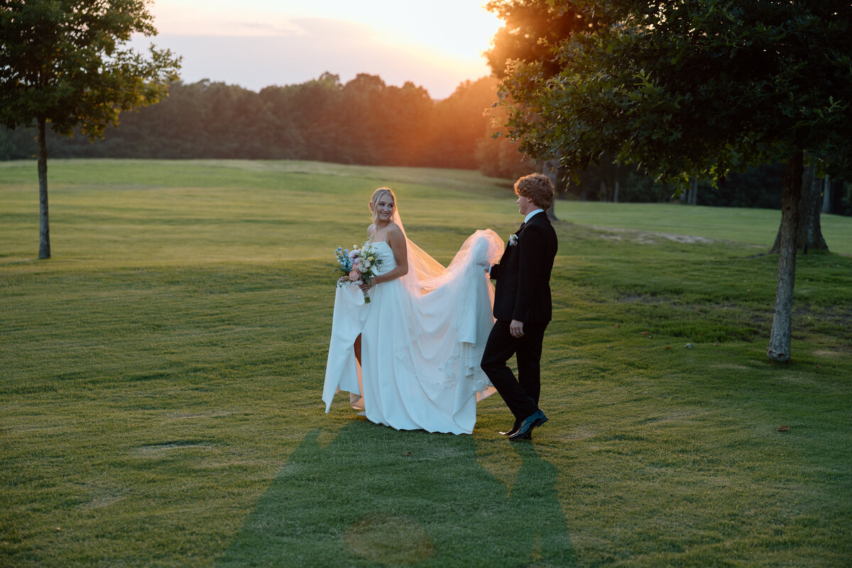 Groom carries the train of bride's dress