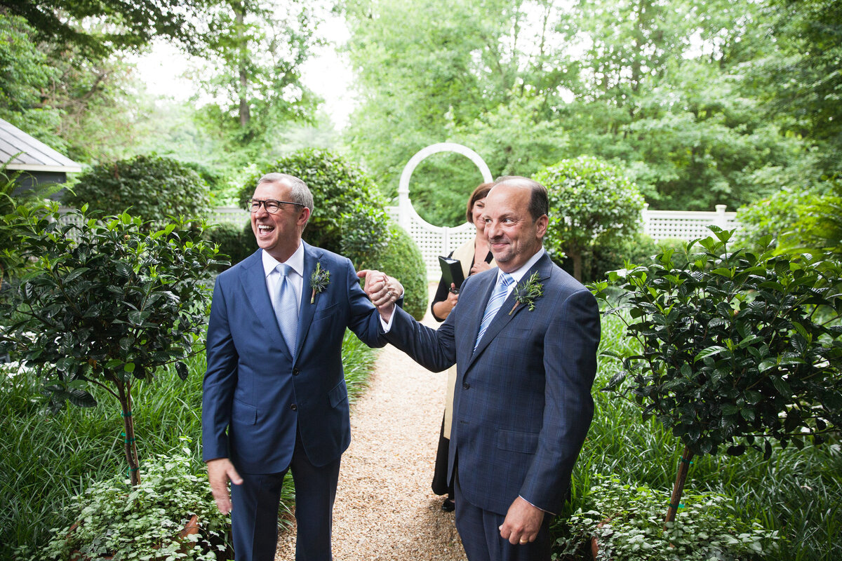 Two grooms holding hands and smiling 