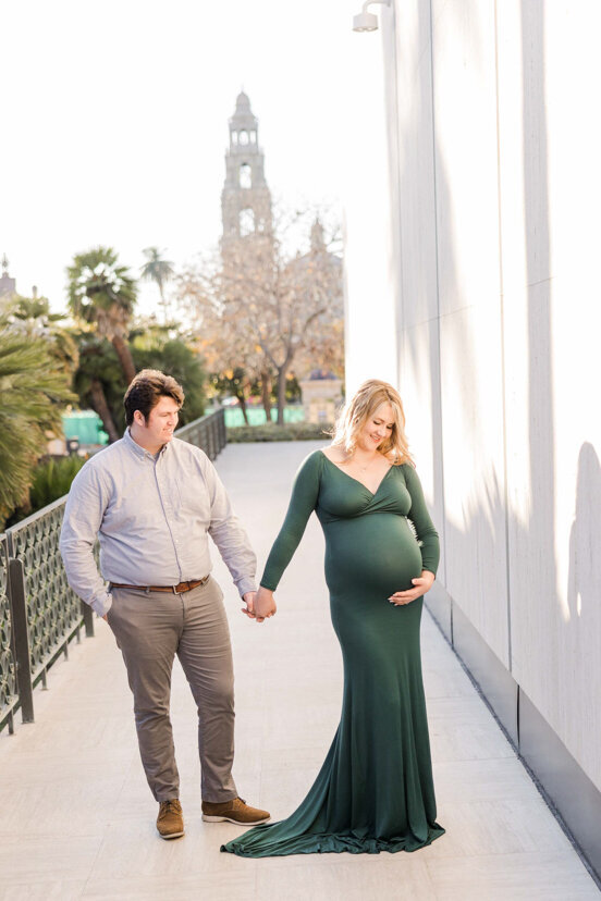 man and pregnant wife in front of balboa park bell tower