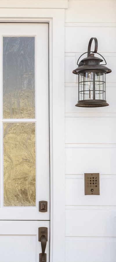6 panel front door with rainwater privacy glass painted white surrounded by white siding and black lanterns 