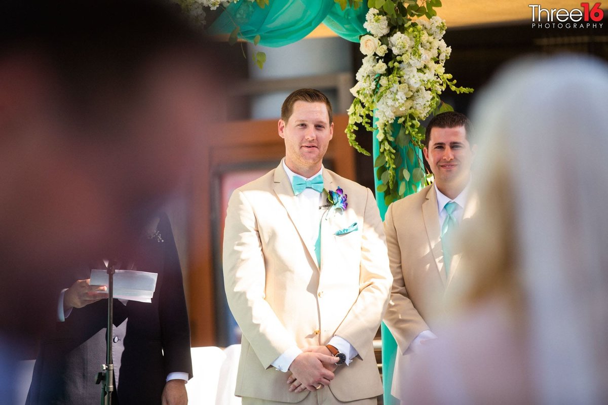 Groom stands at the altar watching his Bride being escorted up the aisle