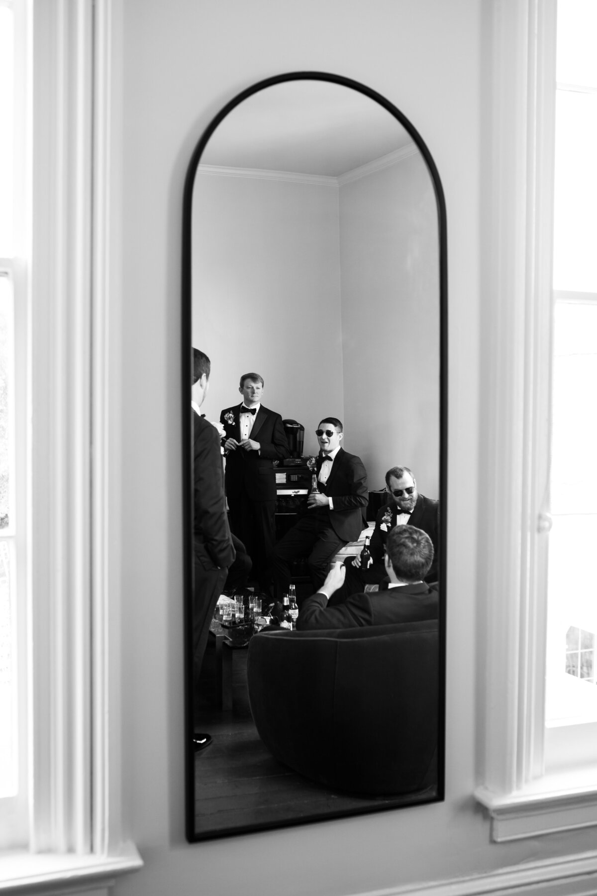 Mirror reflection of a groom with his friends before a wedding ceremony.