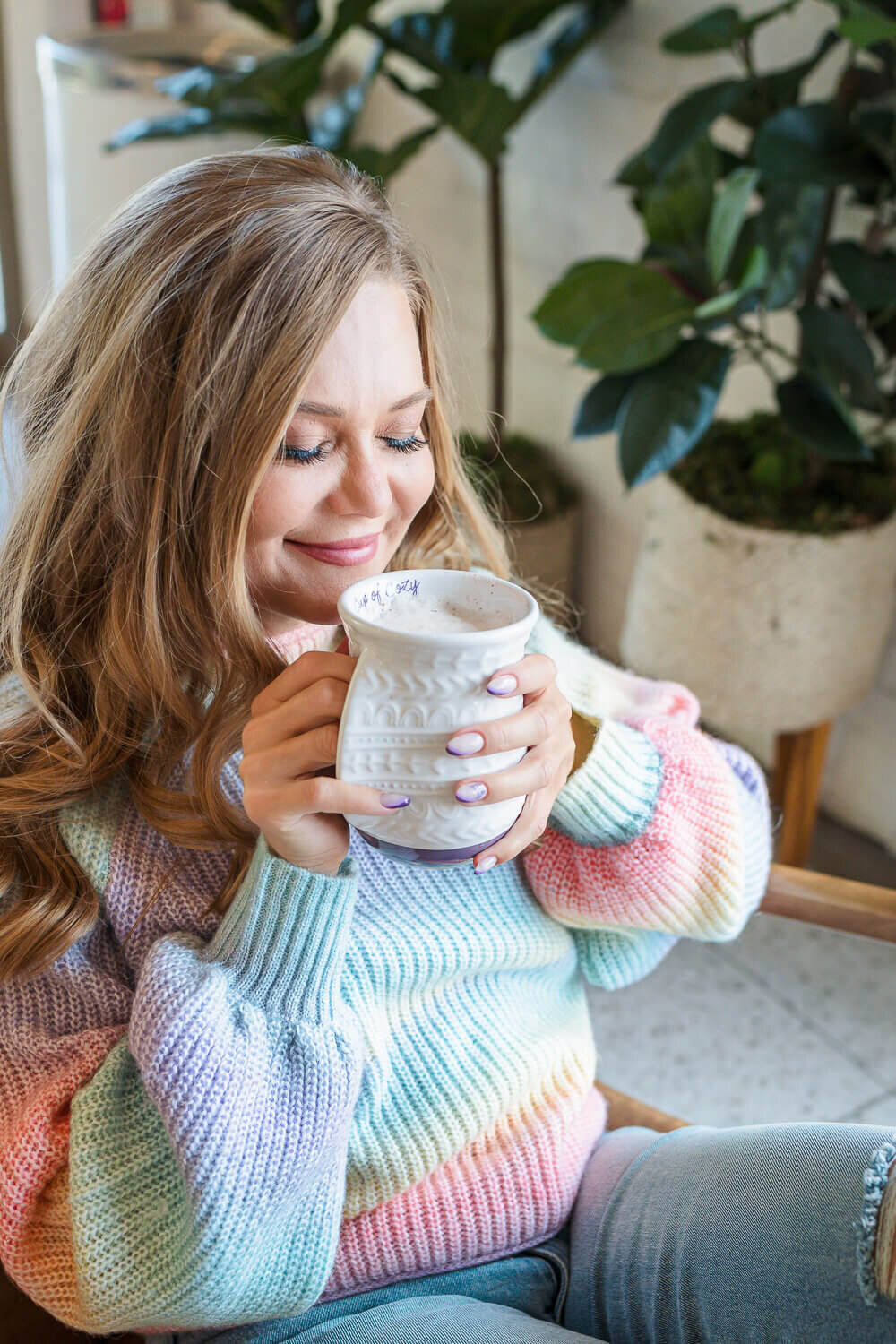 Female coach in cozy sweater enjoying mug of hot chocolate at Deville coffee shop, Kelowna.