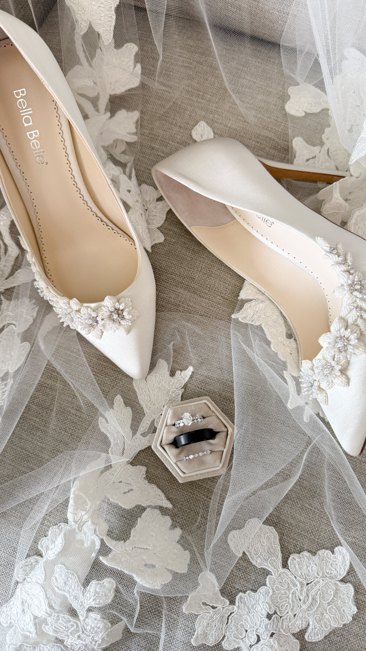 Bride Bella Belle shoes next to a champagne ring box with wedding and engagement rings on a lace veil at Lake San Marcos.