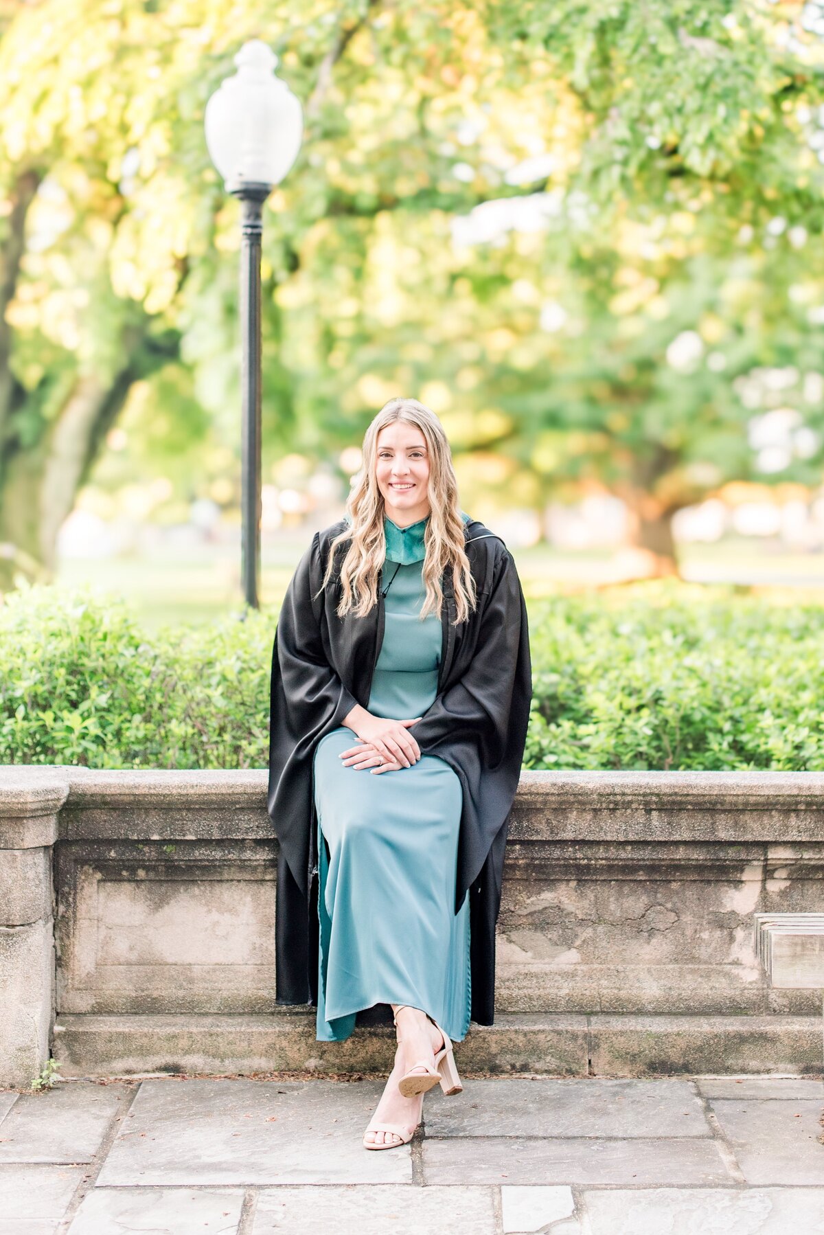 masters graduate sitting on ledge