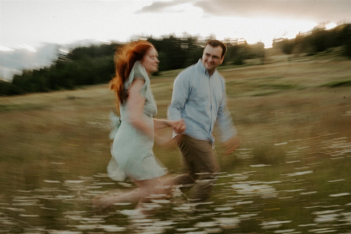 Couple running through a field in the spring