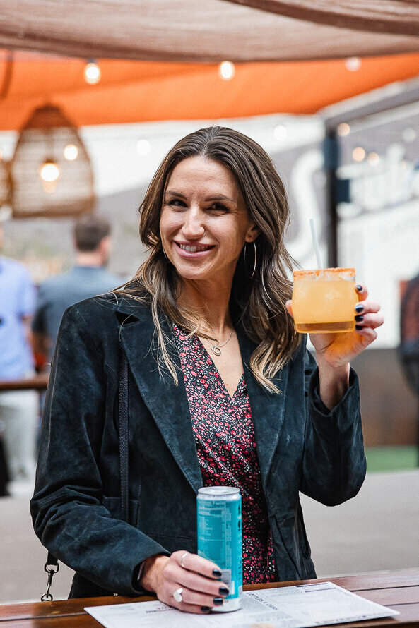 Girl holds up drink and smiles as a part of her company party.