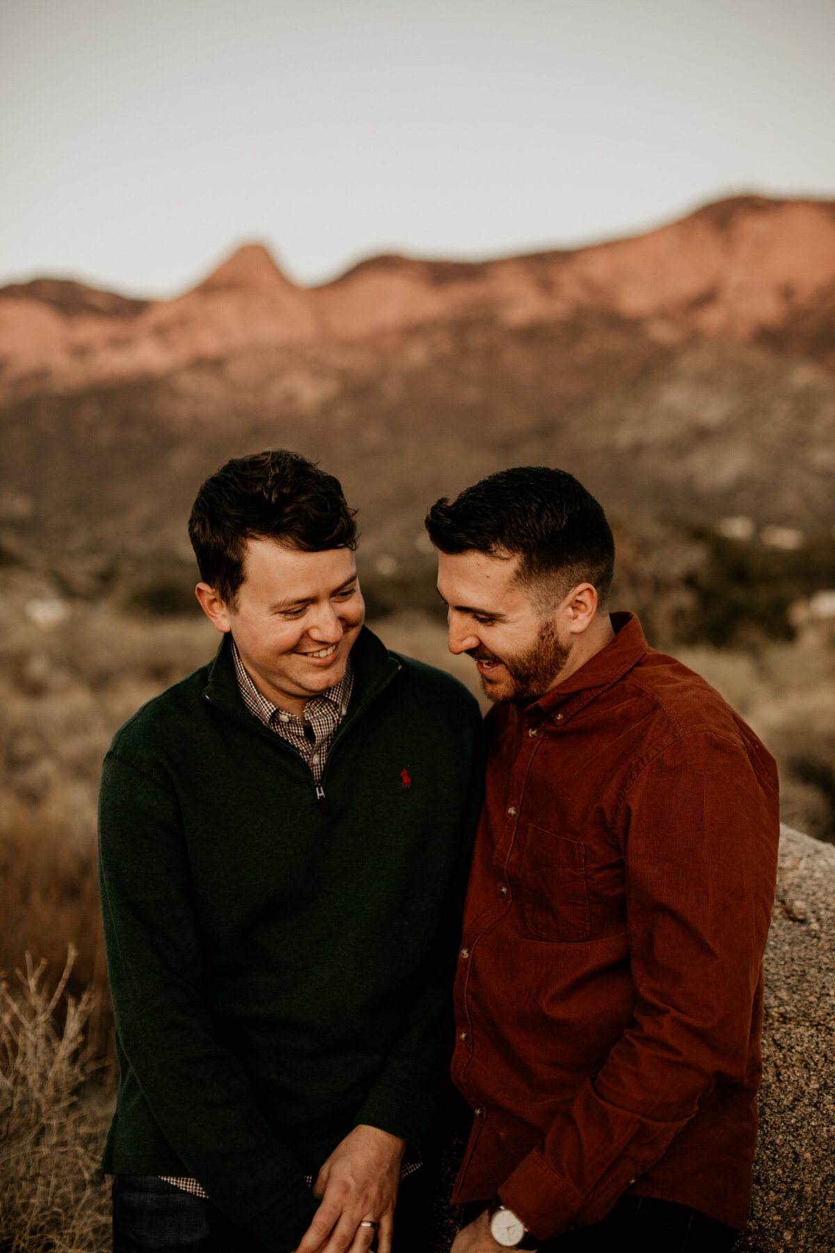two men laughing together in front of the Sandia mountains