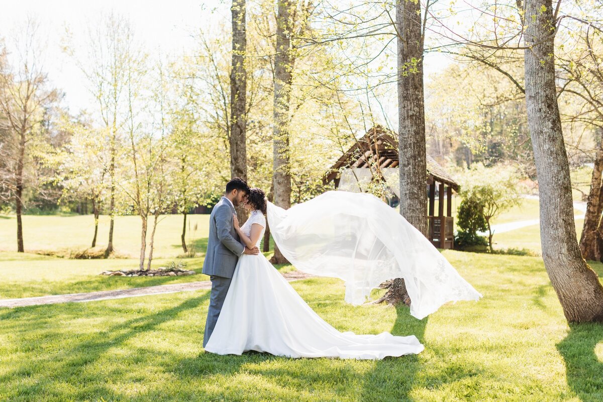 bride and groom kissing while the bride's veil flows in the wind